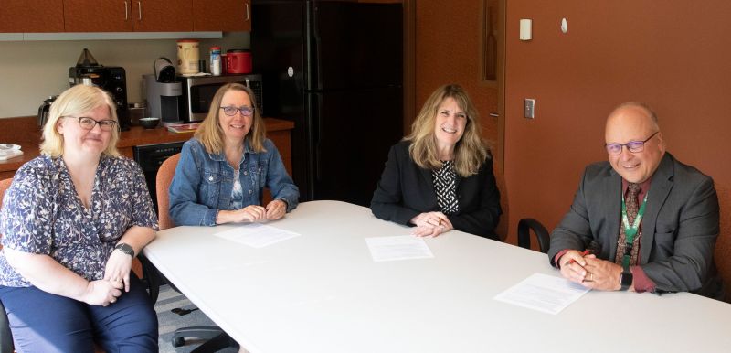 Four people around table smiling