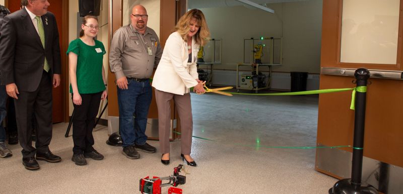 President Kloos, Aaron Barker, Katie Frank, and Chancellor Olson at ribbon with robot