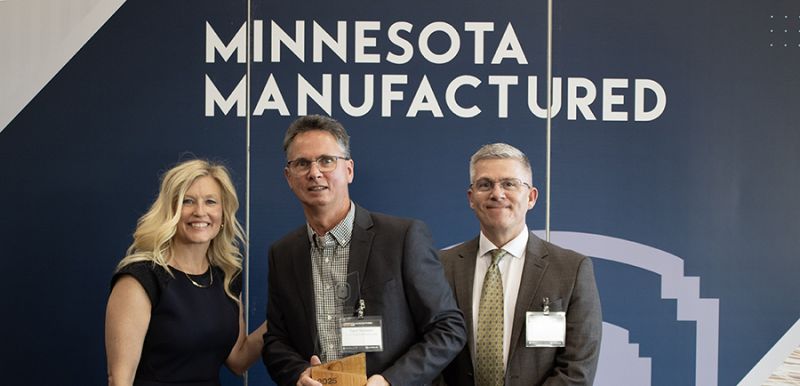 Steve Nusbaum with two others, holding his award and smiling at the camera