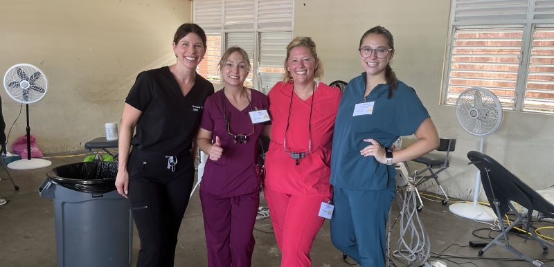 Four dental hygienists in scrubs smiling