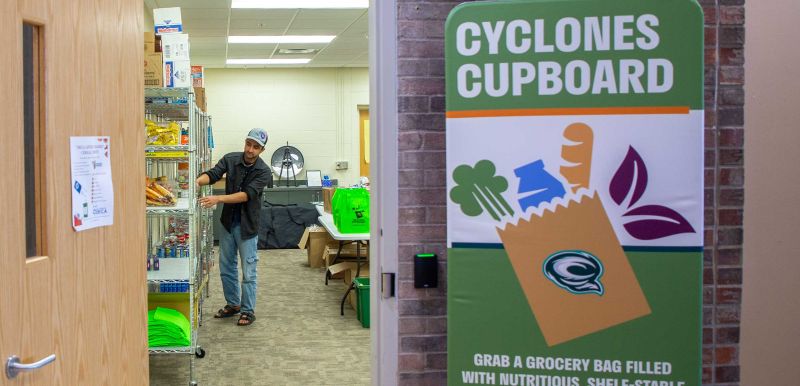 A student worker puts food on shelves in the cupboard