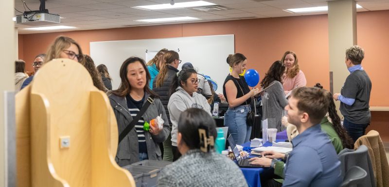 full room with students talking to employers at tables