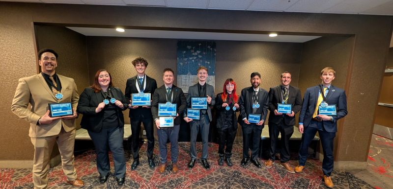Nine DECA students in a row holding their awards