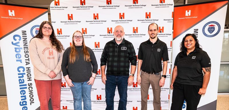 Brian Volkmuth in the middle with four other folks in front of an HTC backdrop