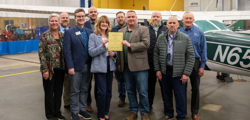 group of AMT advocates and FAA reps holding the SCTCC certificate in front of planes