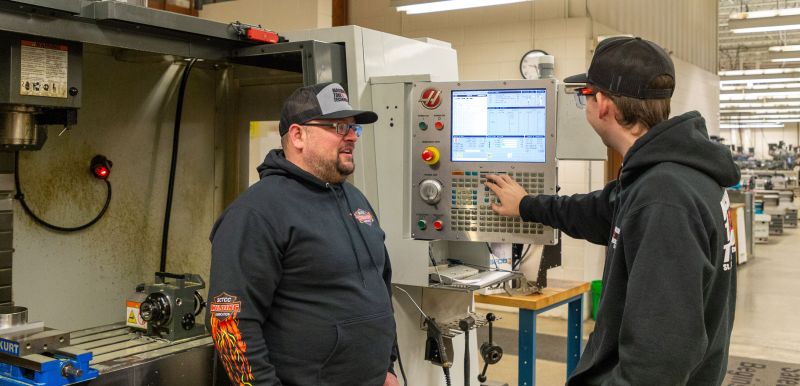two CNC students work on the machine in the SCTCC lab