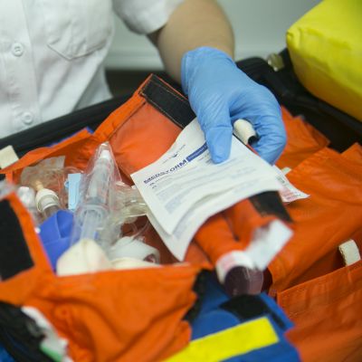 close up shot of gloved hands sorting through medical items in an orange bag