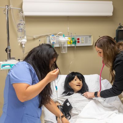 two nursing students working with a Training Mannequin