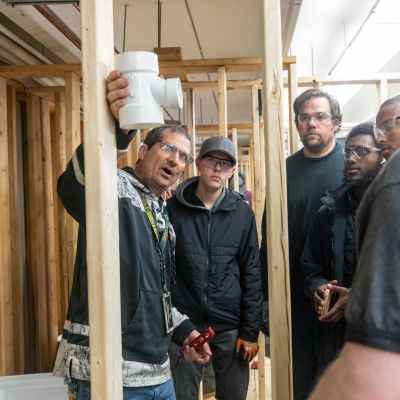 students listening as instructor explains placement of plumbing joint