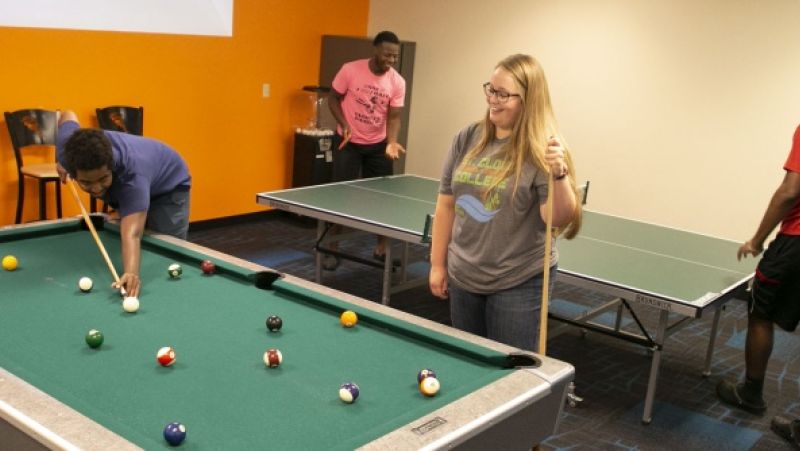 students playing pool and foosball in the student lounge