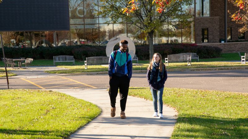 two students walking with Northway building in background