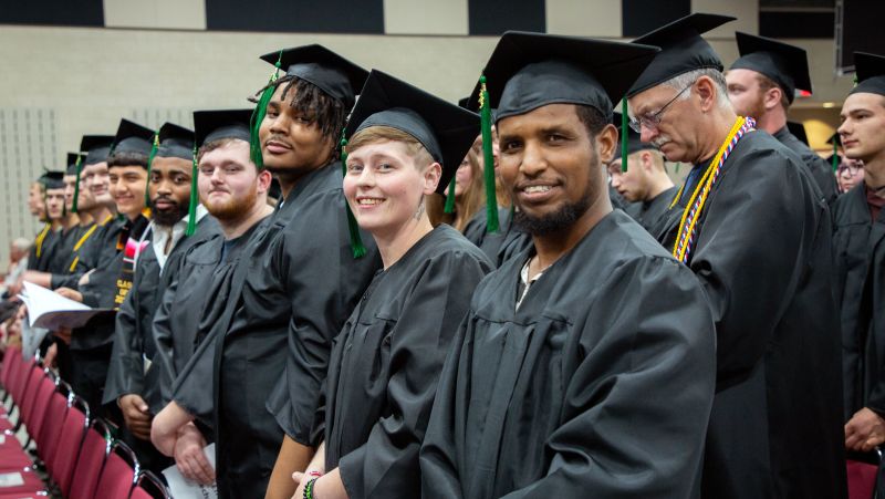 Graduates in regalia smiling at camera