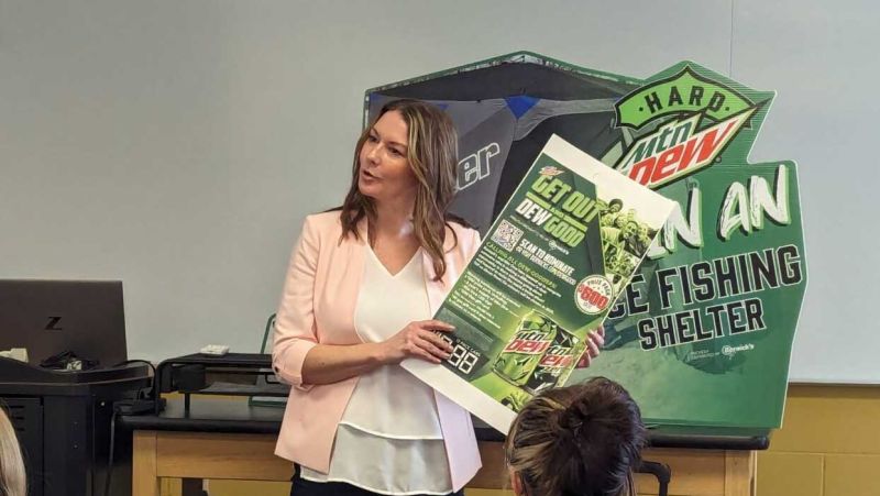 Eve Miller holds poster in front of classroom