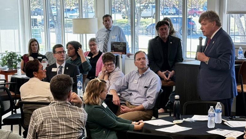 a crowd of people in the library with chancellor olson speaking with a microphone