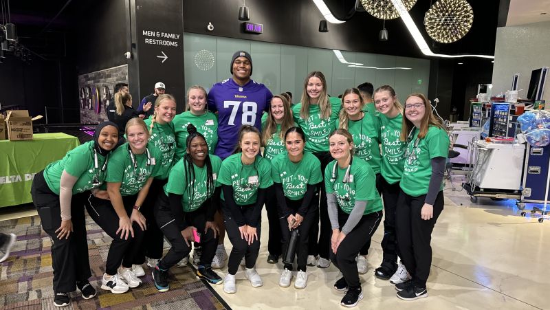 Dental hygiene students in two rows with MN Vikings player in back