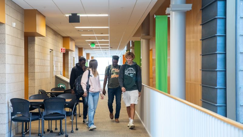 group of 4 students with backpacks, wearing SCTCC shirts and sweatshirts walking in a hallway