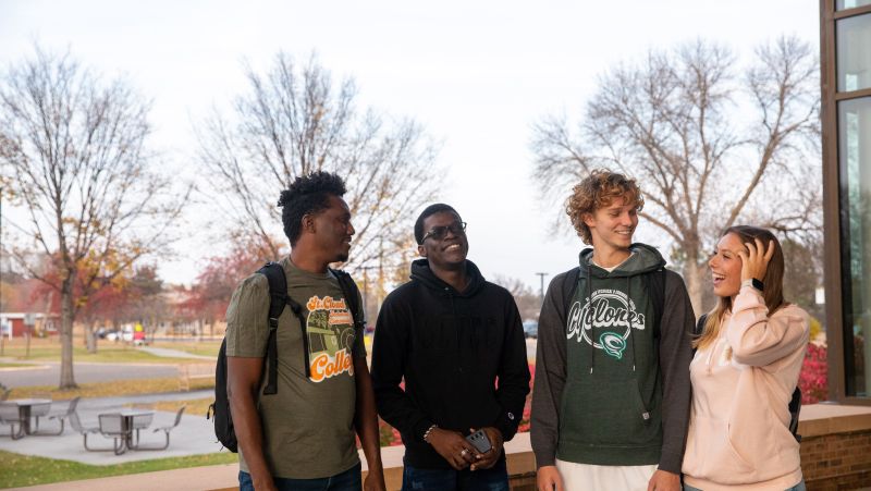 group of 4 international students outside door one, laughing in conversation