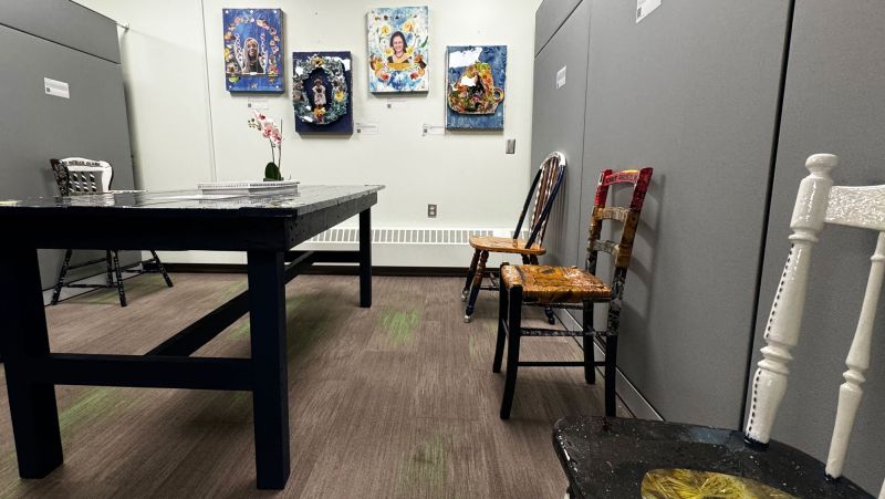 Azania's art in the MCC - table, three chairs, and four portraits on the wall