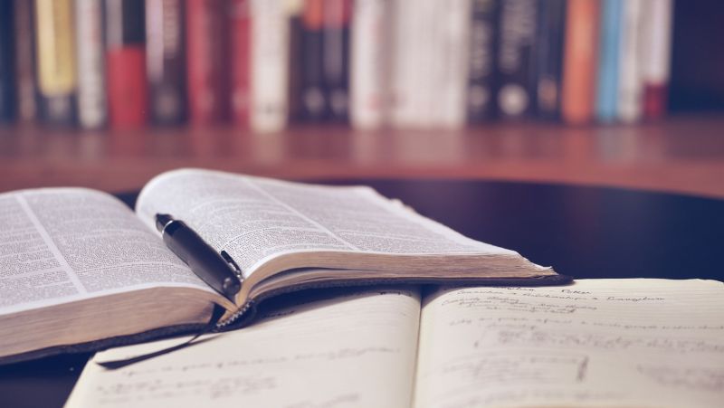 image of books in a library, two books are opening. One book for taking notes and the other for studying.