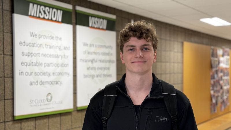 Micah Davis in front of mission and vision, smiling