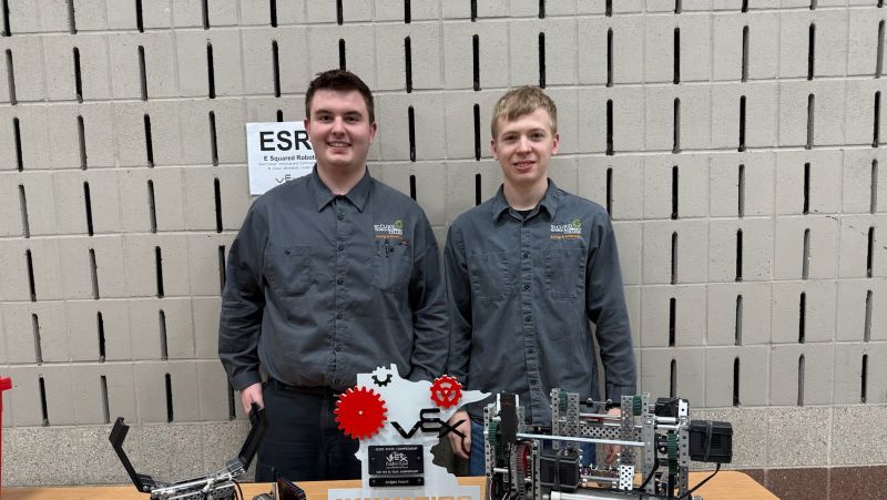 Two students with robots and award