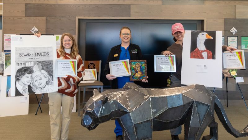 Three winners from art contest pose with art and certificates