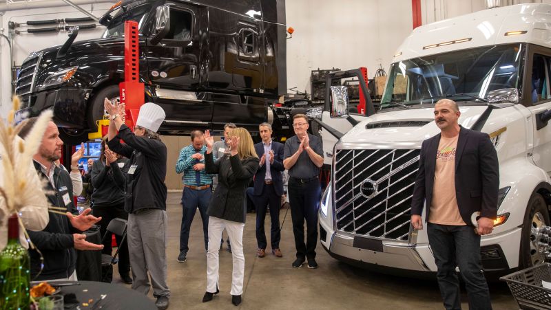 Several people clapping with semi trucks in background