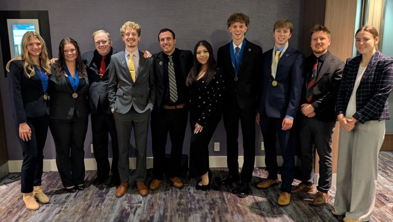 Group of 10 DECA students in a row, smiling at the camera.