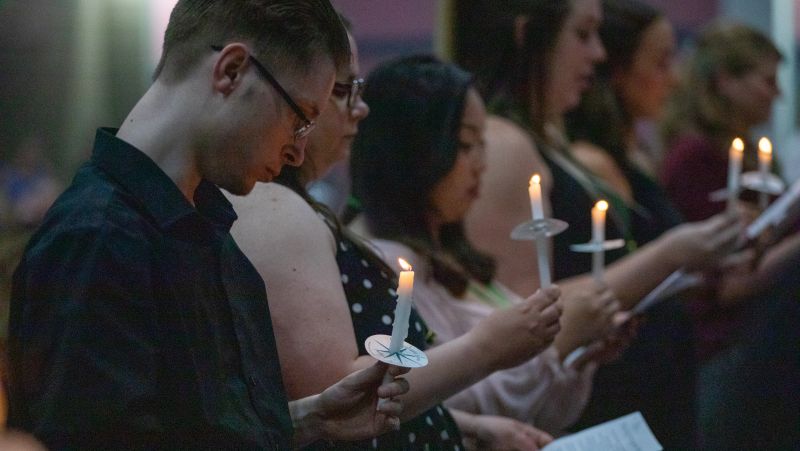 students hold candles at pinning ceremony