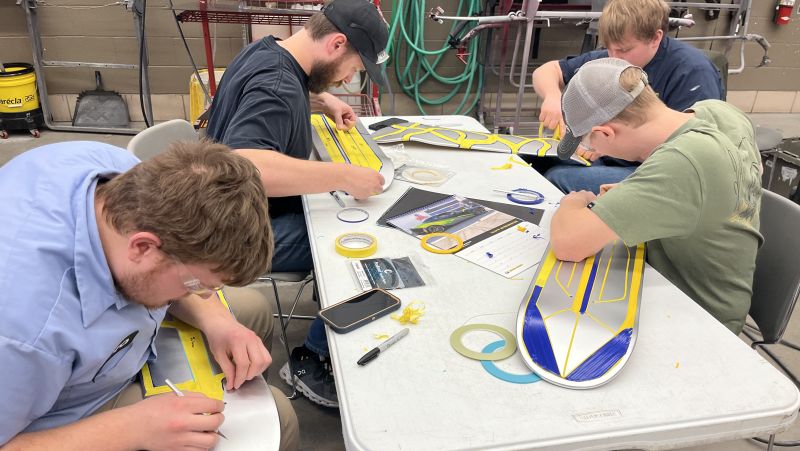 four auto body students working on designs for their skateboards