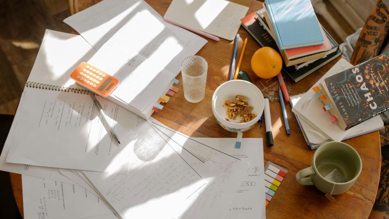 desk full of study supplies. Paper, snacks, books, & computer