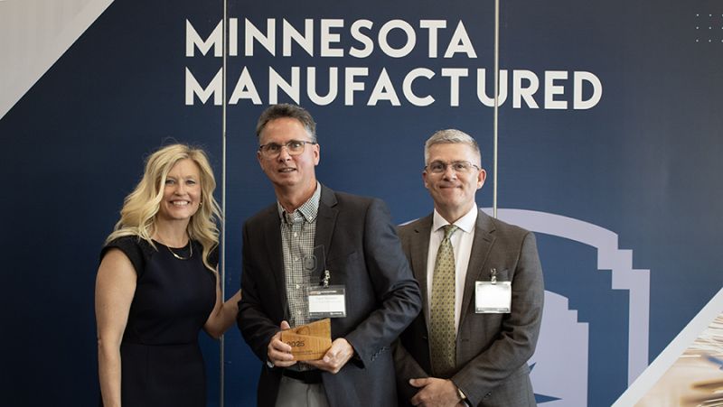 Steve Nusbaum with two others, holding his award and smiling at the camera