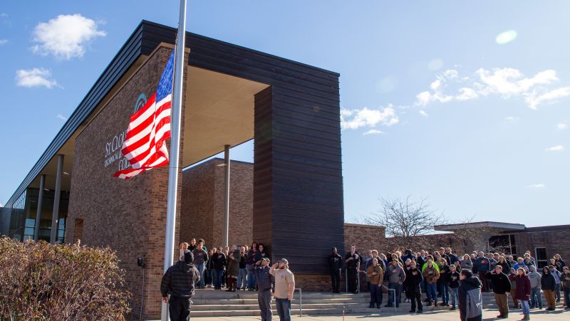 group of people looking up at flag at main entrance