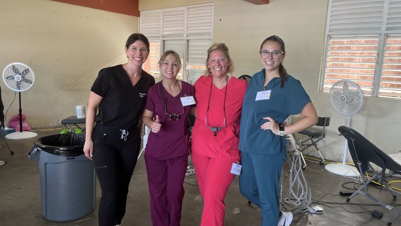 Four dental hygienists in scrubs smiling