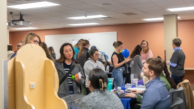 full room with students talking to employers at tables