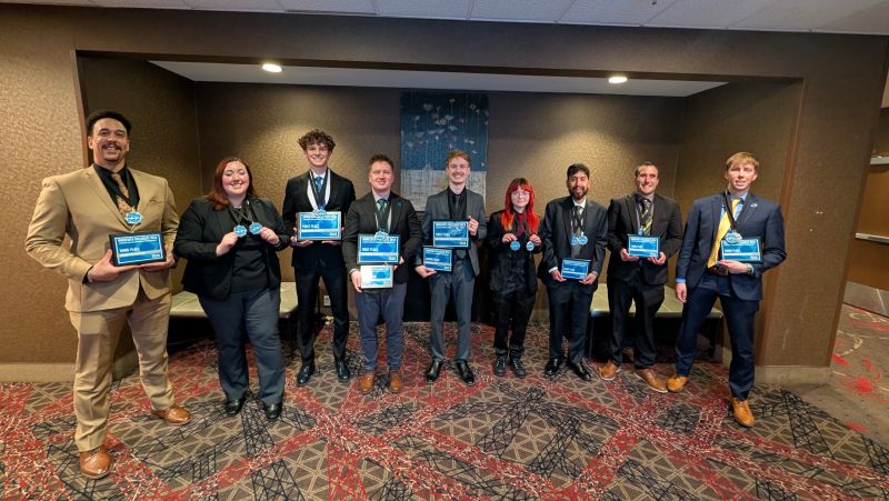 Nine DECA students in a row holding their awards