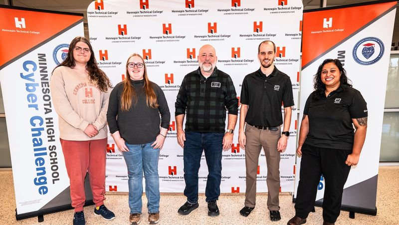 Brian Volkmuth in the middle with four other folks in front of an HTC backdrop