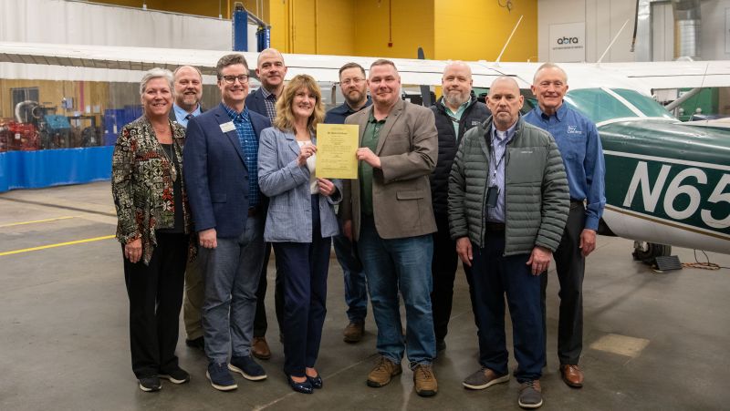 group of AMT advocates and FAA reps holding the SCTCC certificate in front of planes
