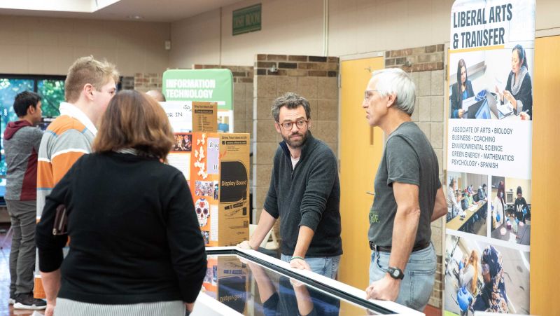 Two instructors chat with visitors at the open house