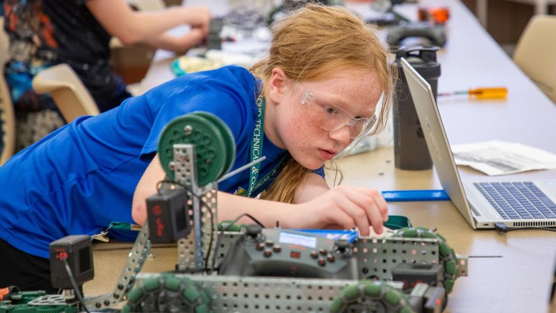 girl focused on fixing robot