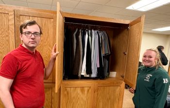 Two students holding open closet door