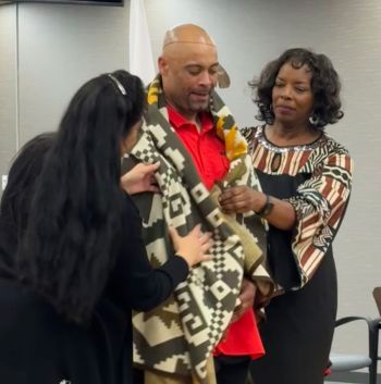 Two women draping Kevin with a blanket