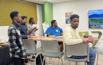 Five men sit at a table eating food