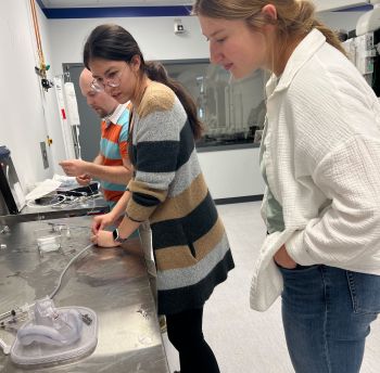 Three students at a lab table working on an instrument