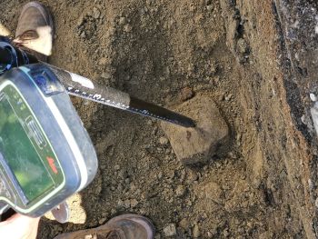 marker being unearthed with land survey instrument on it