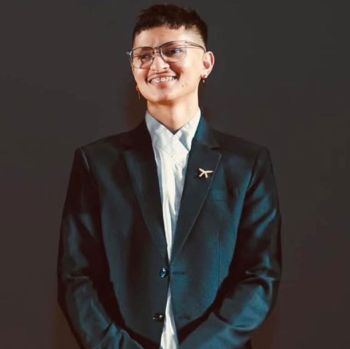 Aveen in a suit against a backdrop