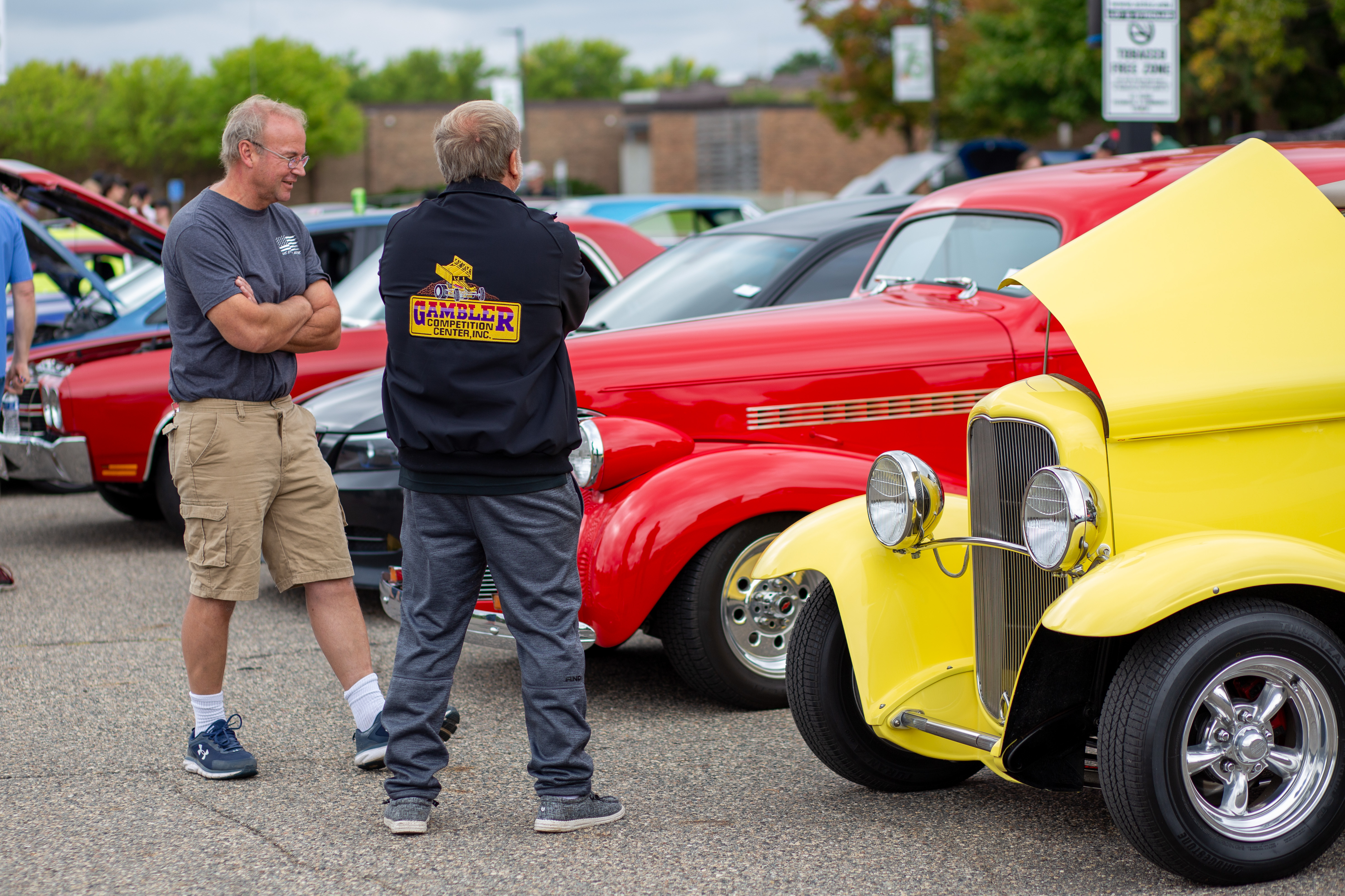people talking in front of vintage cars