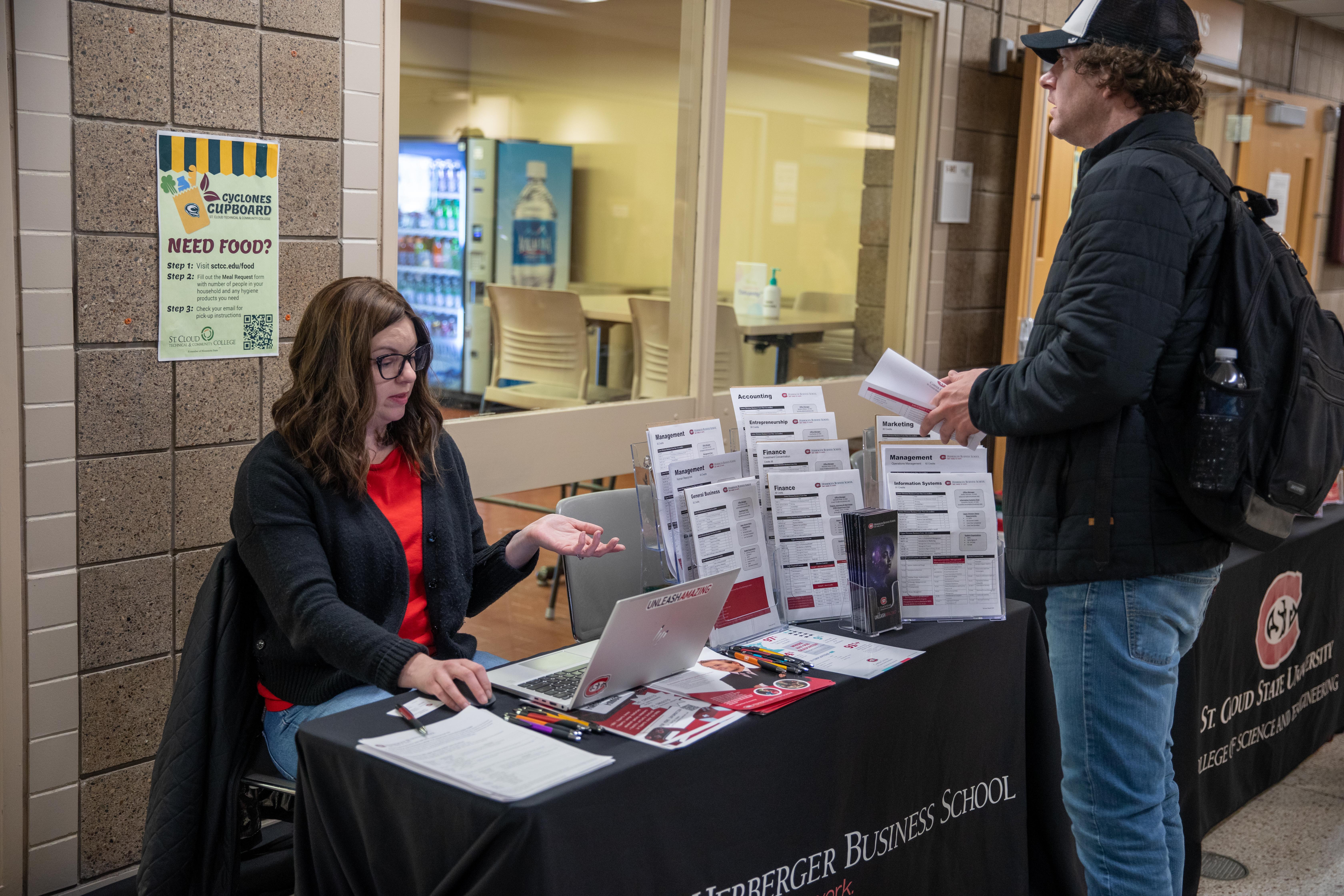 two people talking at a table full of college transfer information