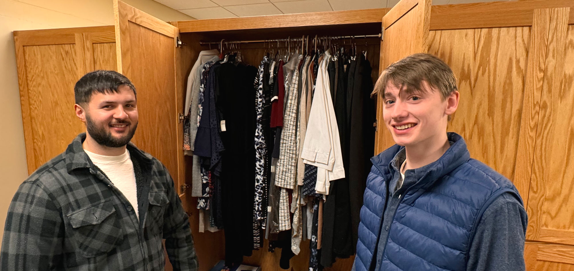 Two students holding open middle closet doors