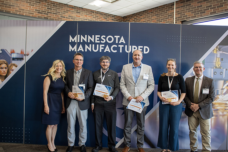 Steve wtih the large group of winners, posing in front of manufacturing backdrop
